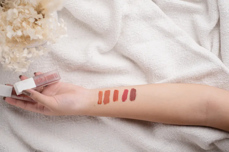 Five shades swatched down a forearm resting on white linen.