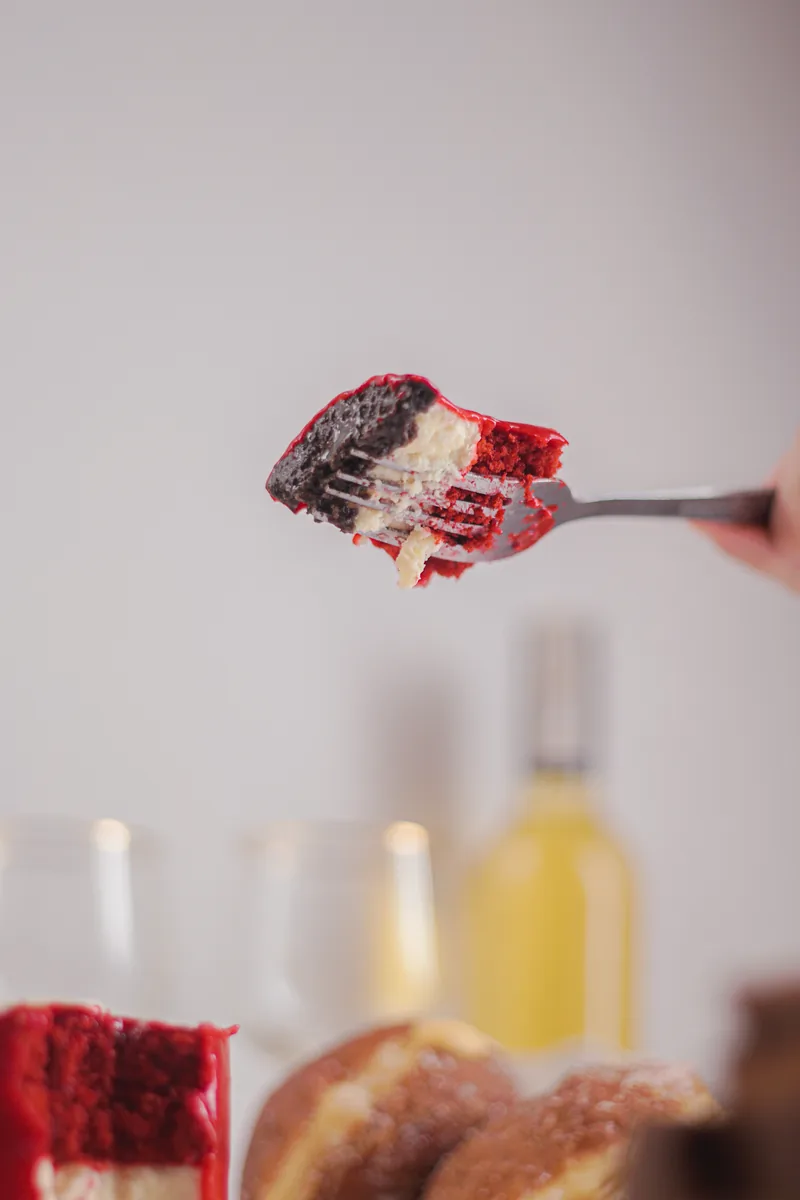 A fork holding one red velvet bite, the box soft behind.