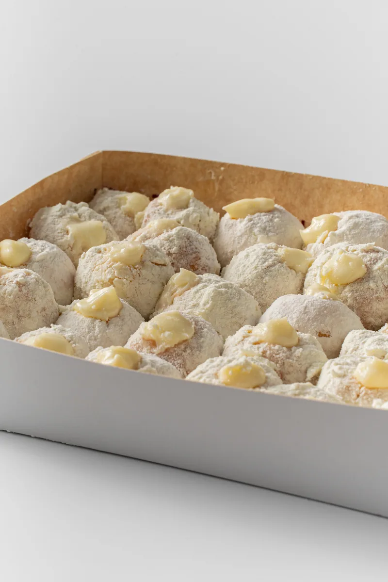 A white box packed with rows of powdered bavarian buns.