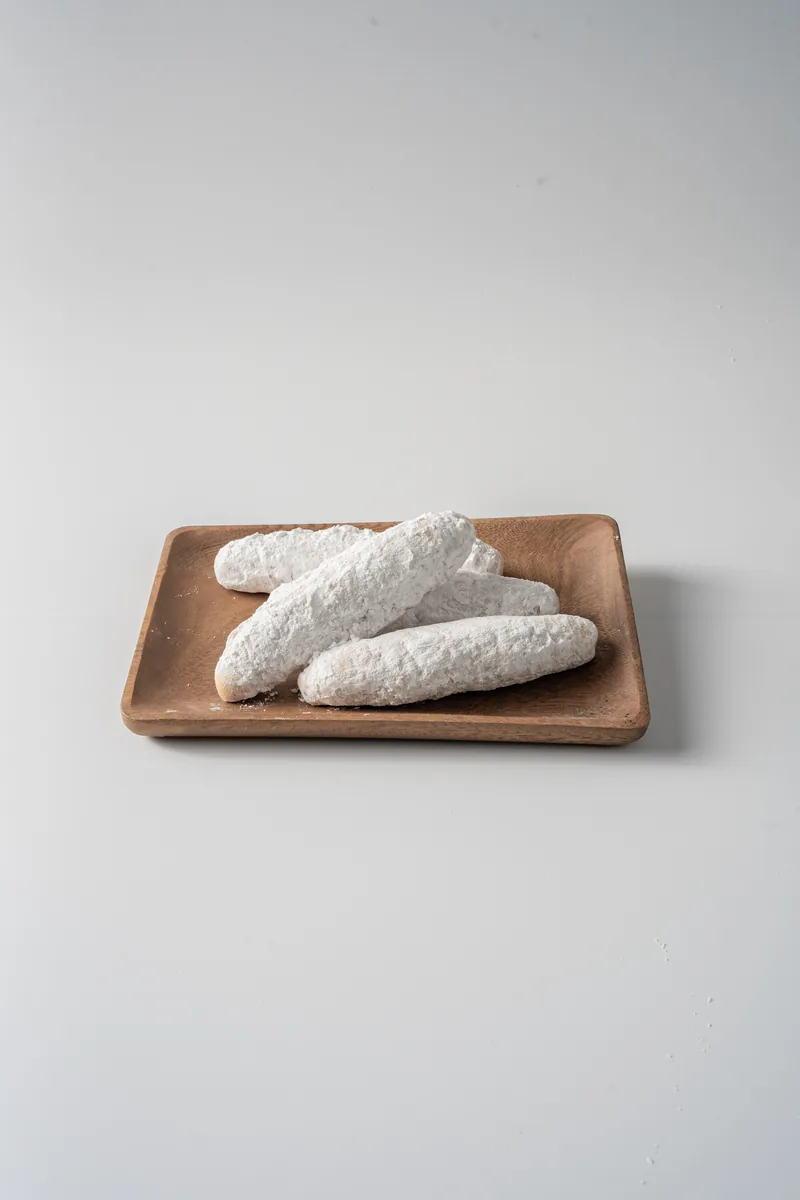 Powdered donuts arranged on a wooden board.