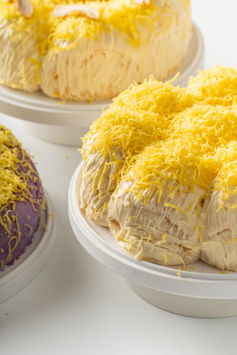 Ensaymada varieties grouped with an ube loaf and small bowls.