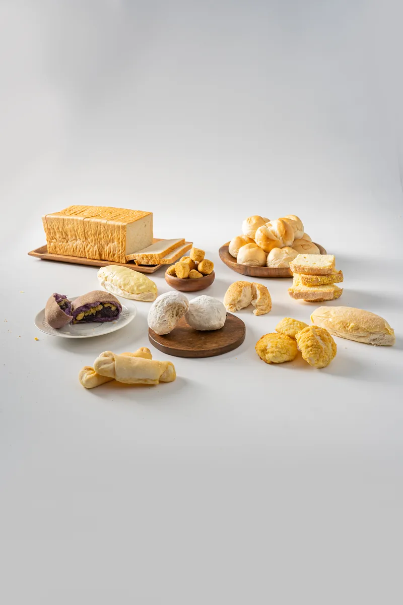 The full LA Bakeshop range arranged on white: loaf, ensaymada, pandesal, rolls and cakes.