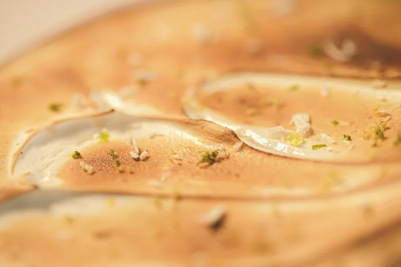 Macro of a torched meringue surface, scorched ridges and scattered lime zest.